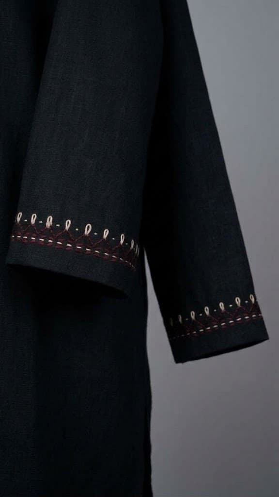 Close-up of the hand embroidered cream and maroon border on the sleeves of the black top